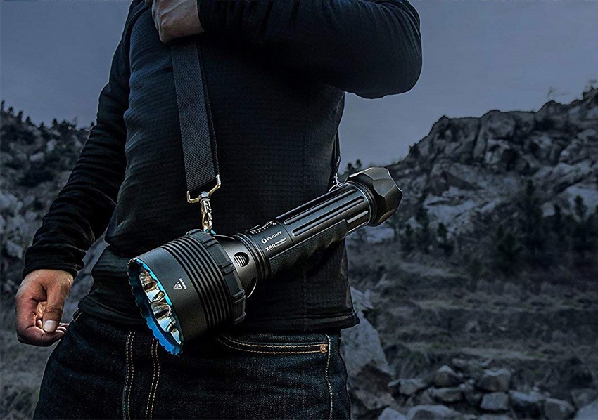 picture od a man in the mountains holding an Olight X9R Marauder Flashlight 