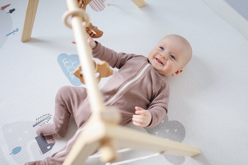 picture of a baby on the floor playing with wooden toys