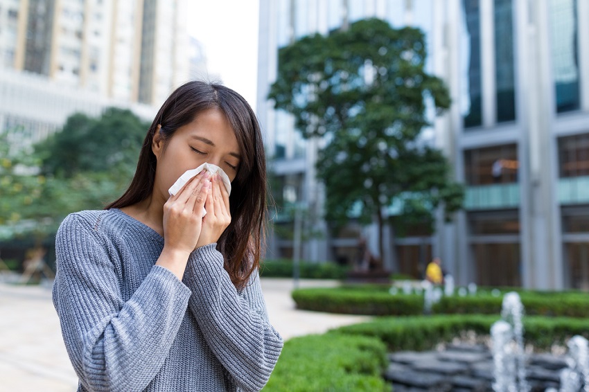 picture of a woman wiping her nose in a park between buildings 