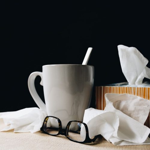 picture of a ceramic mug, napkins and glasses on a white table and black background