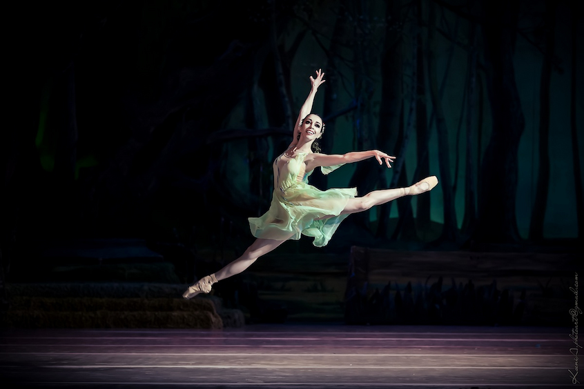 ballerina doing jump in beautiful stage clothing