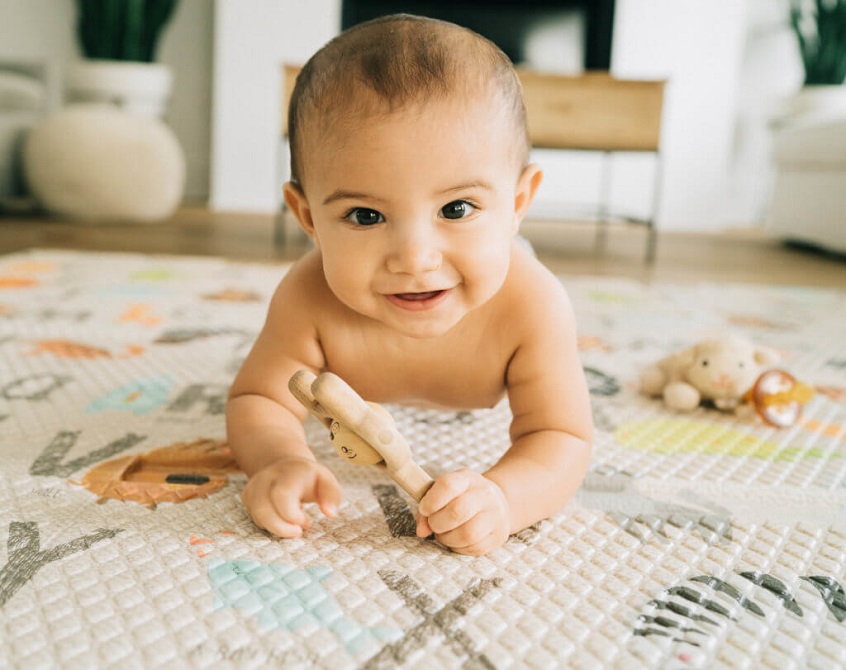 smiling baby on crawling mat looking at camera 