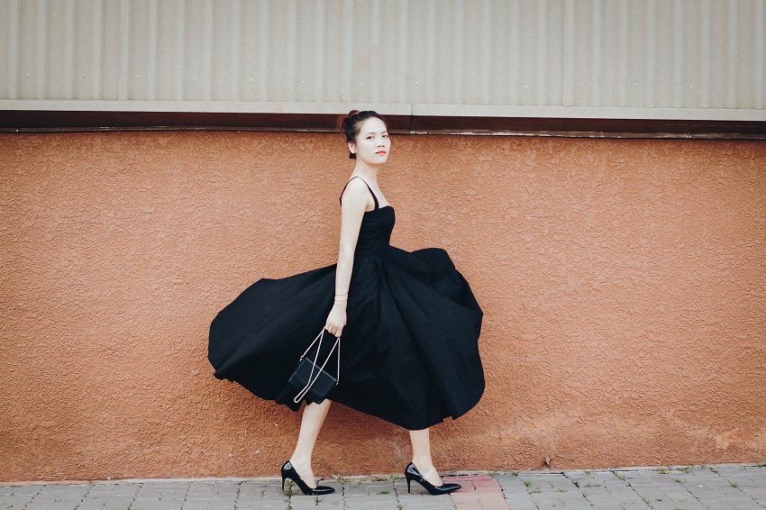 picture of a woman wearing a black dress walking on a sidewalk in stilettos