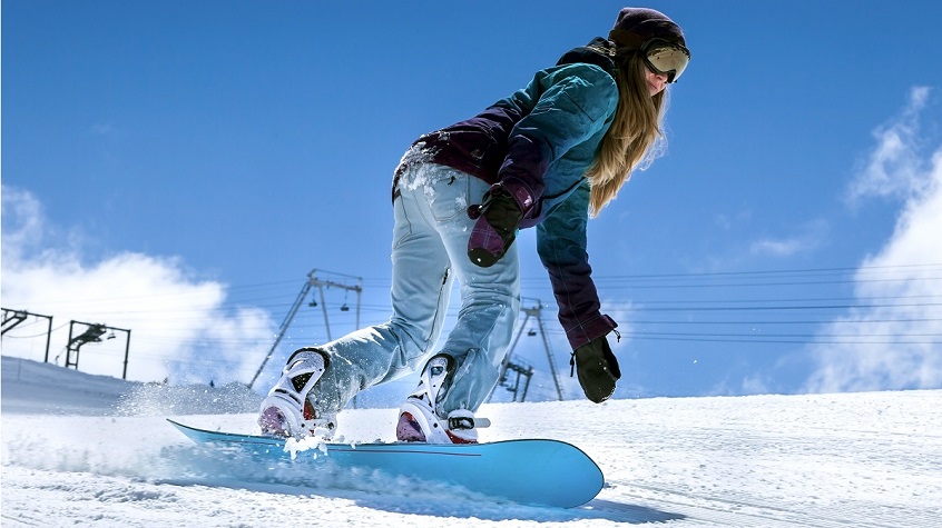 woman in motion on snowboard in mountains on the slopes