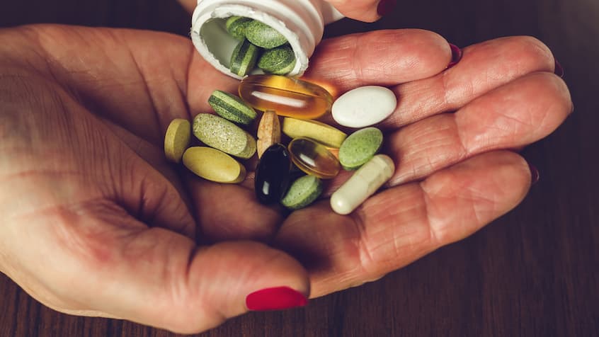 woman's hand full of vitamins of different types