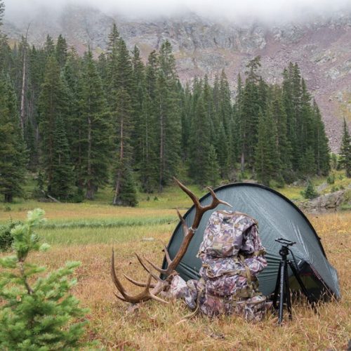hunting tent in a wilderness with a backpack outside of a tent