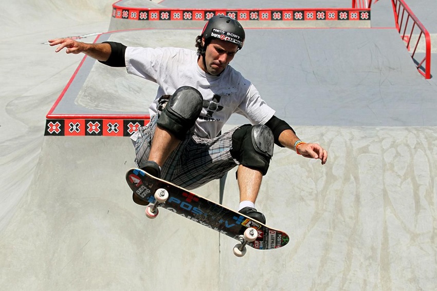 picture of a men skateboarding in a skate park wearing protective gear 