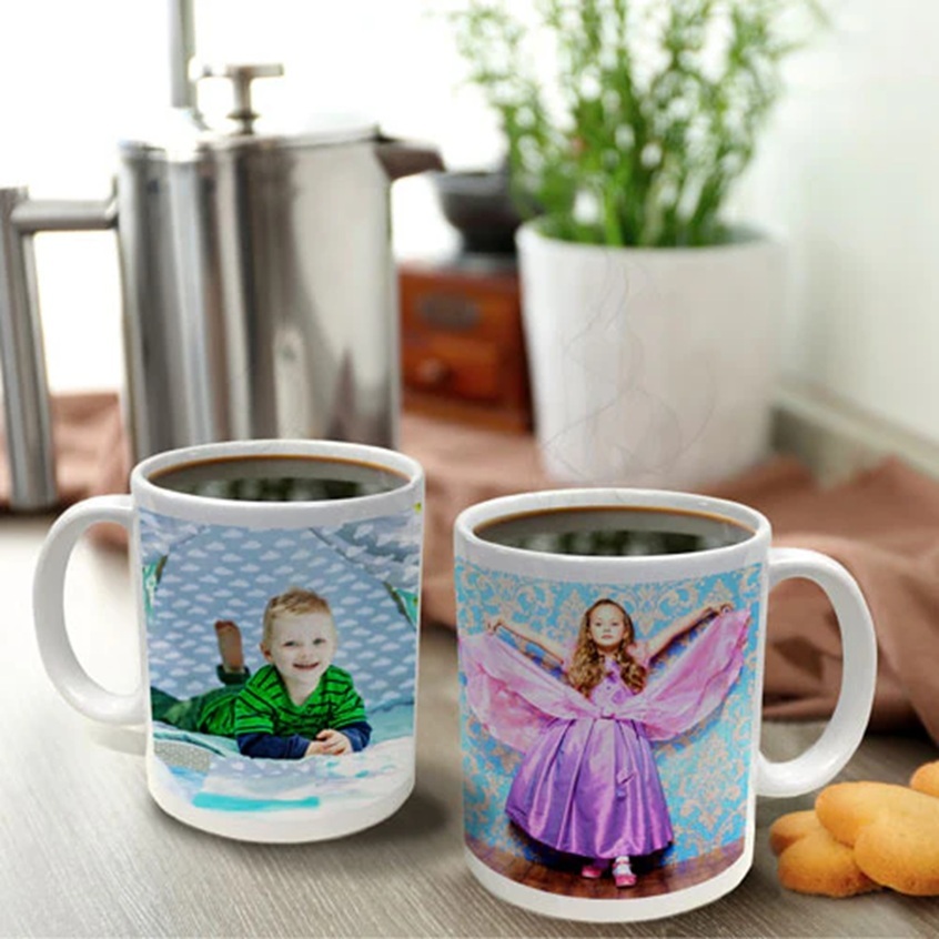 2 mugs with photos of kids on a table